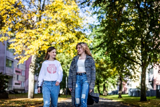 Två unga tjejer promenerar i en allé på Råslätt
