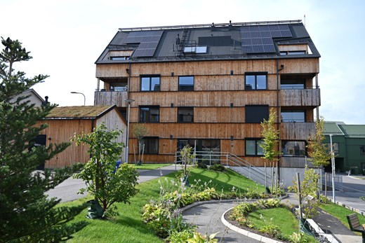 Träfärgat flerbostadshus med solpaneler
