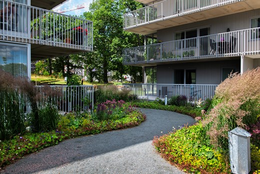Trevåningshus med långa balkonger och grönskande trädgård