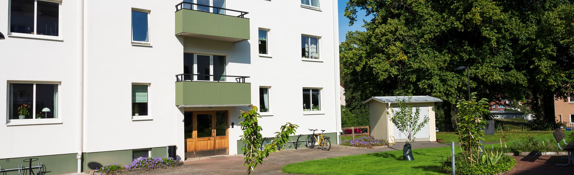 Vitt flerbostadshus med gröna balkonger