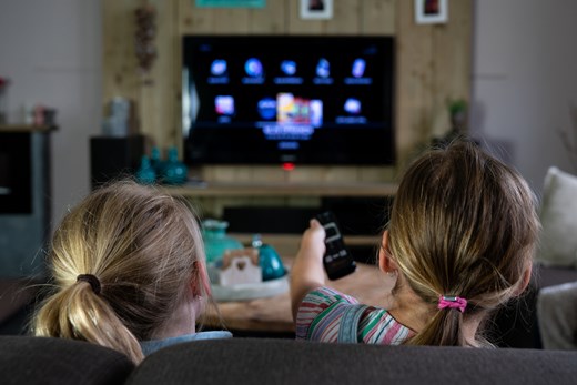 Två barn i soffan framför tvn